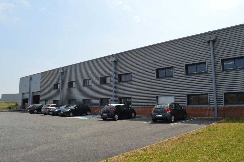 Le site SNV à Comines : bâtiment industriel de production et de logistique, avec ses quais et son parking.
